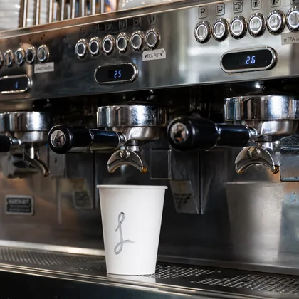Espresso pouring into a CAFÉ LARA takeaway cup
