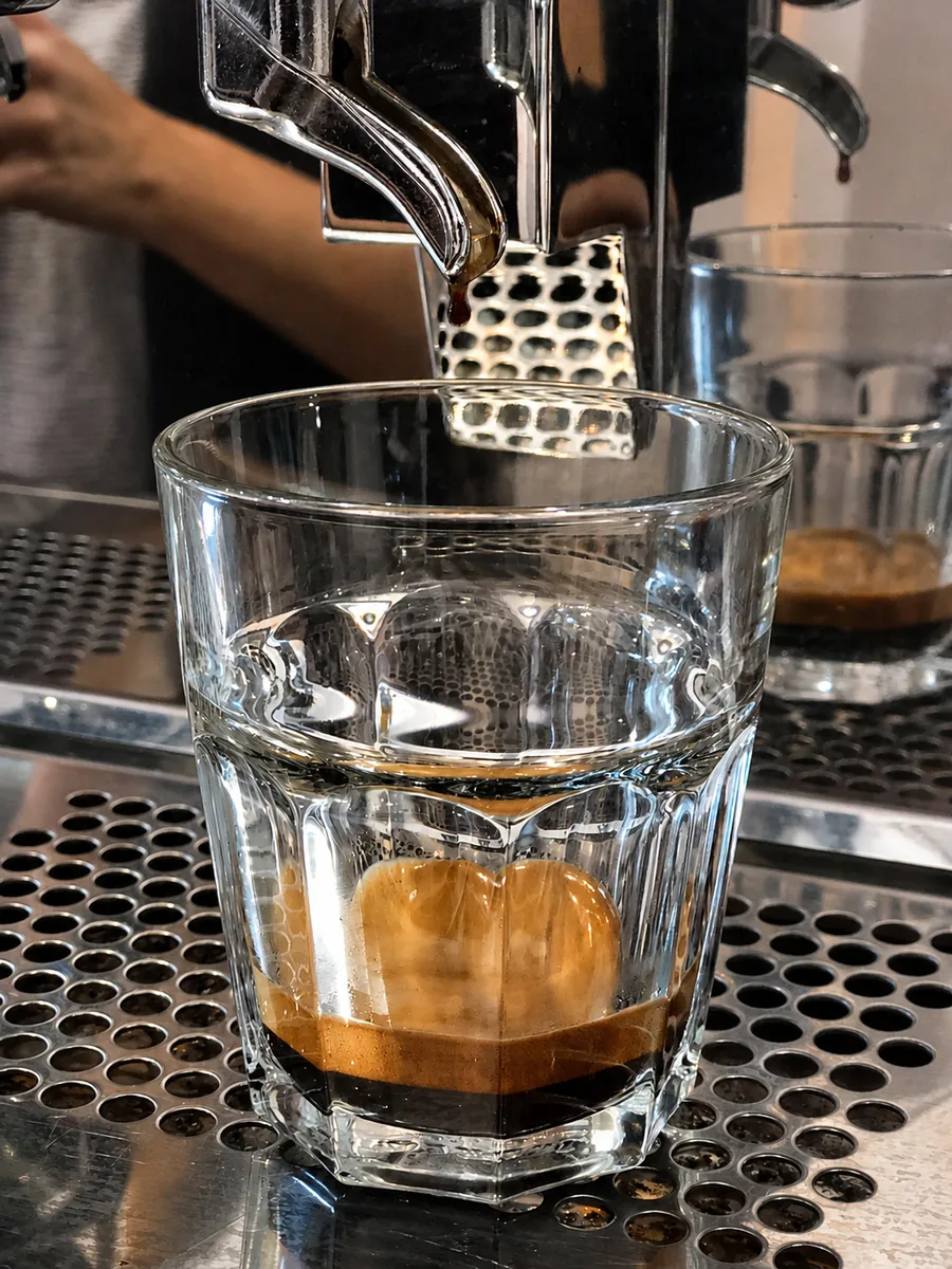 Espresso pouring into a glass from the café coffee machine