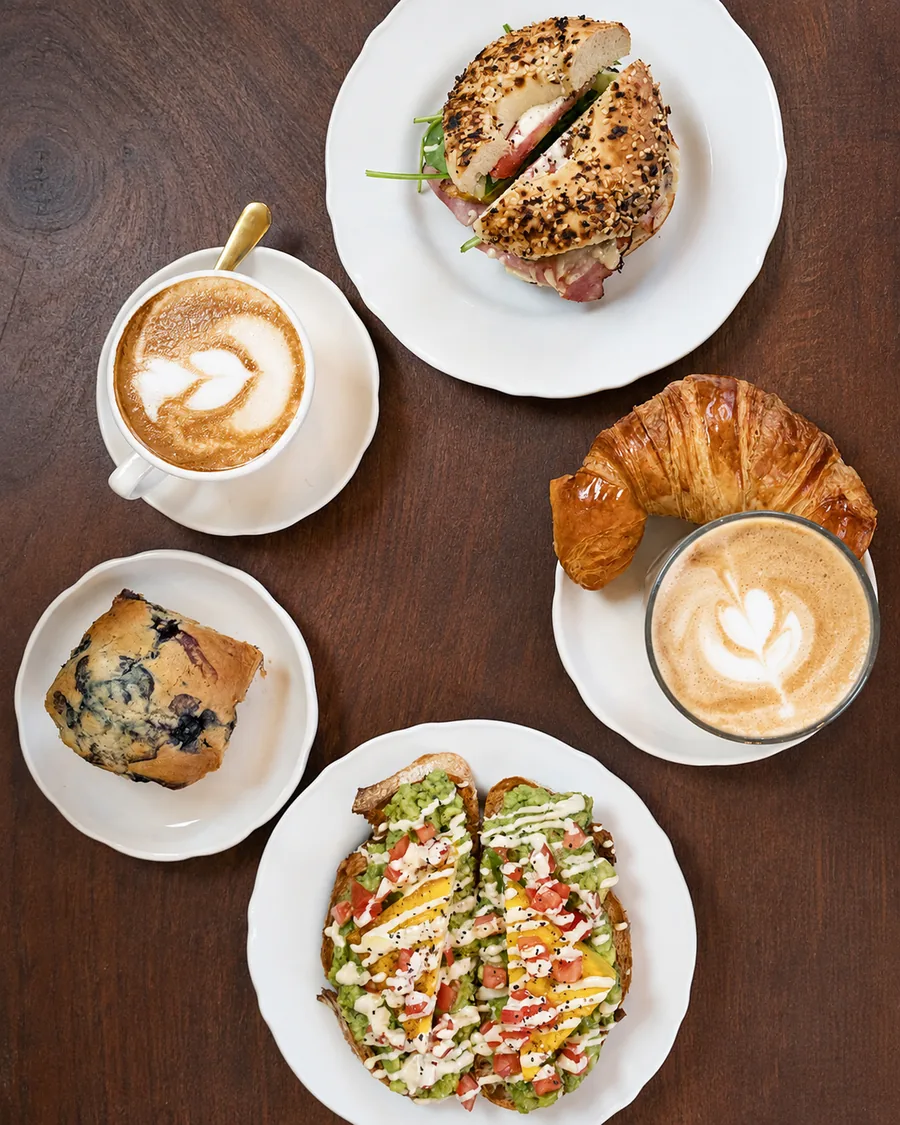 Coffee, pastry, a bagel and toast arranged on a café table