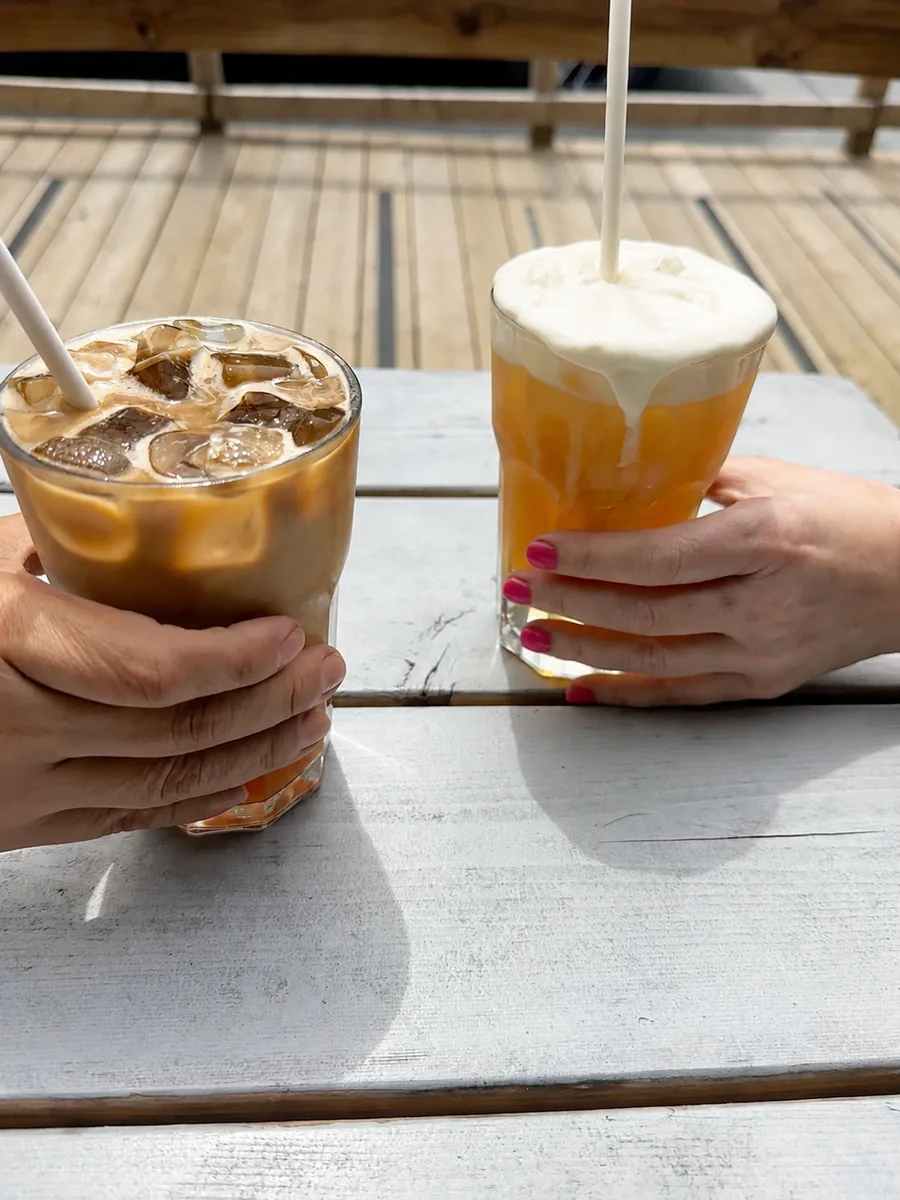 Two cold drinks shared across a sunlit café table